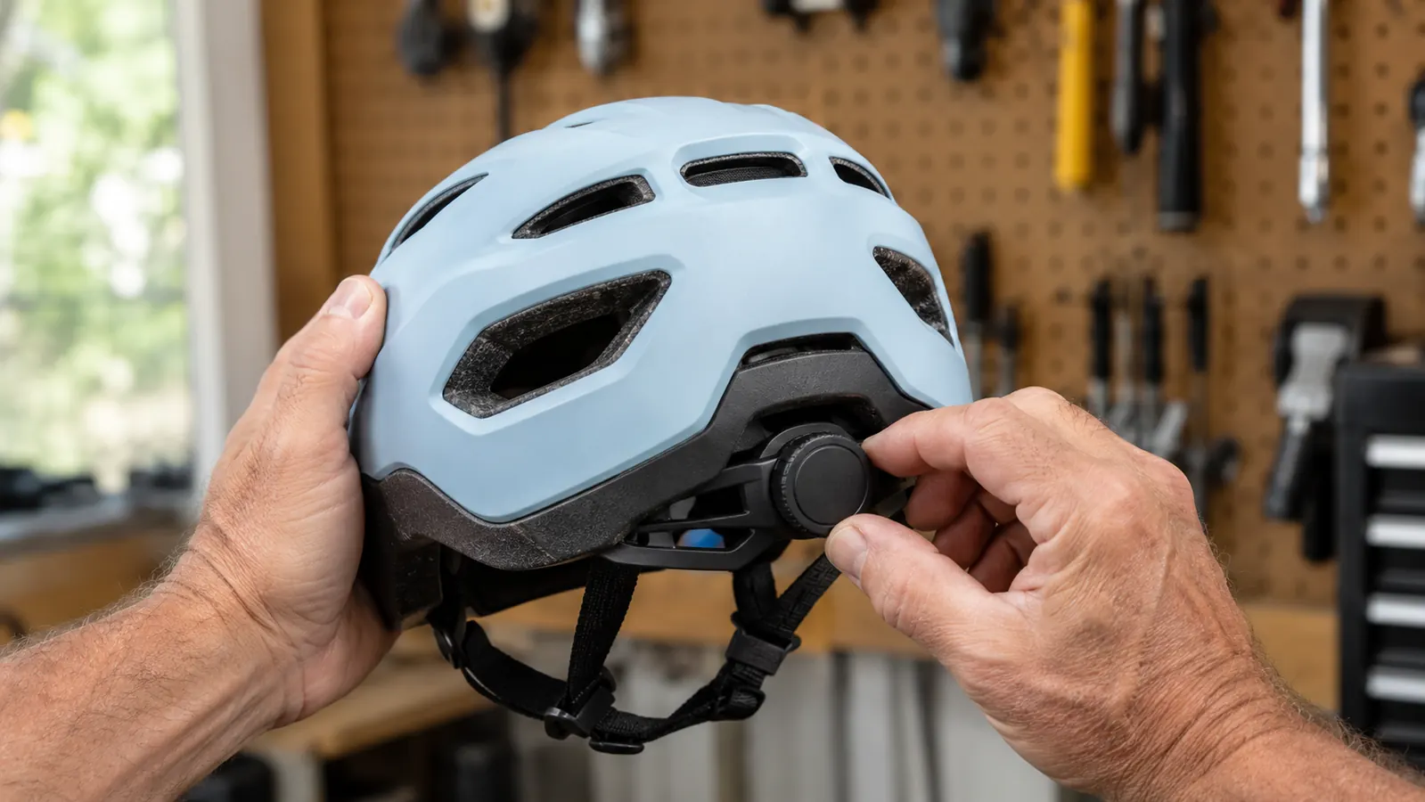 An adult turning the fit dial on the back of a kids multi-sport helmet