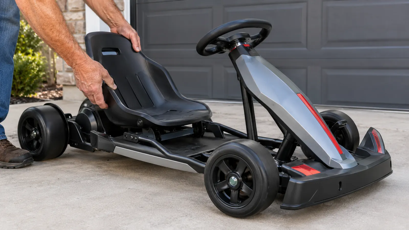 An adult adjusting the seat on an electric drifting go kart on a concrete pad